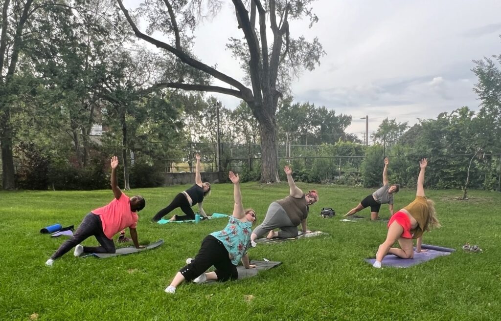 A group of women holding a yoga pose on mats in a park
