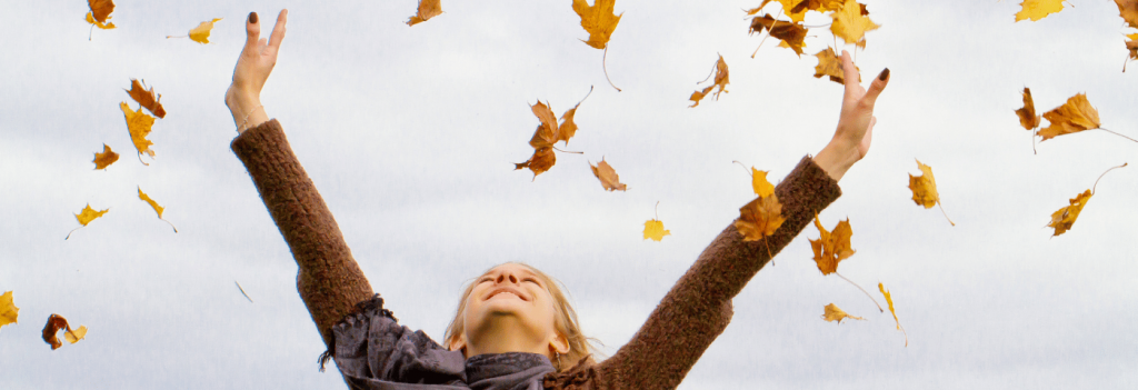 Woman throwing fall leaves in the air